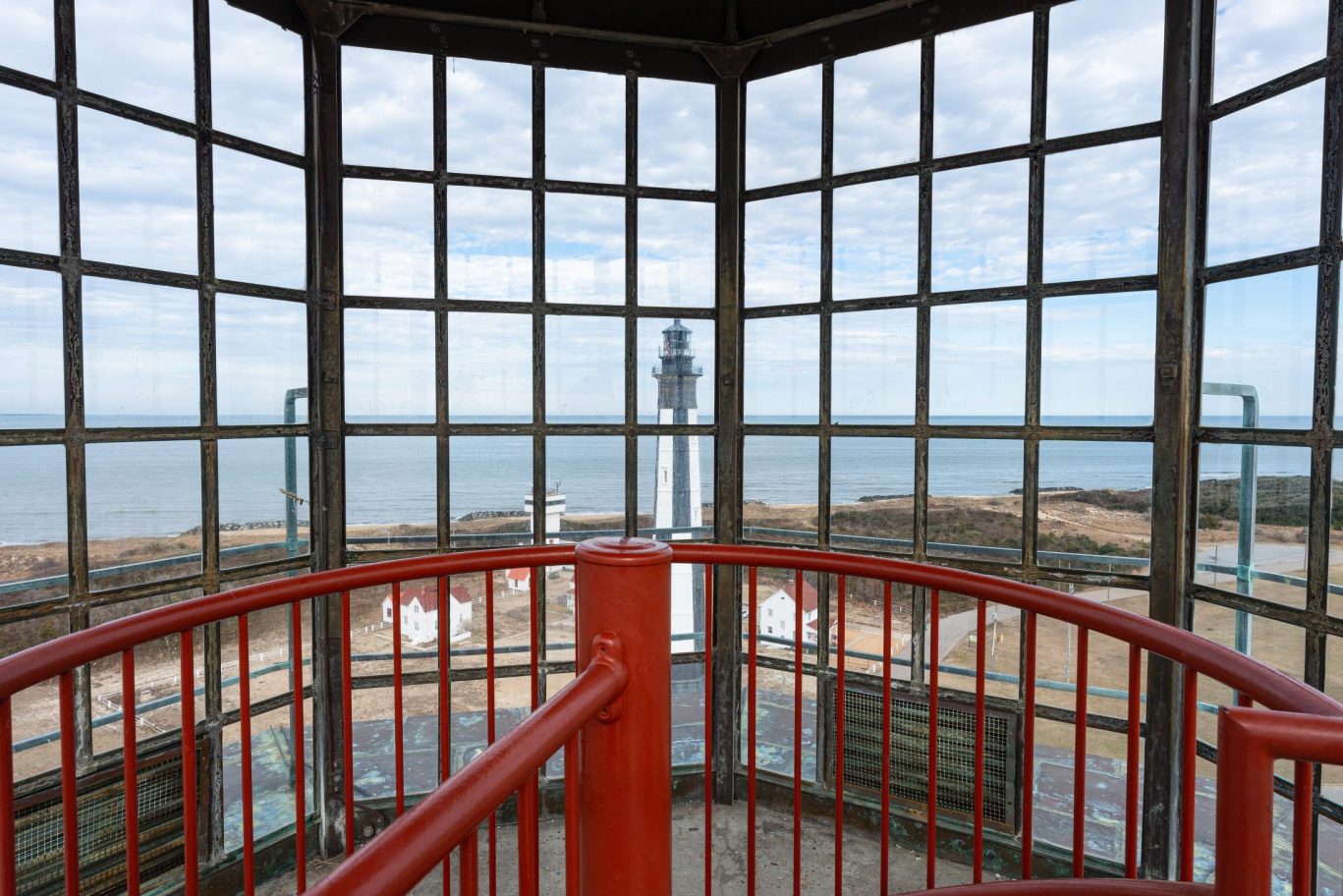 Looking out from lighthouse interior with red railing and panoramic coastal views.