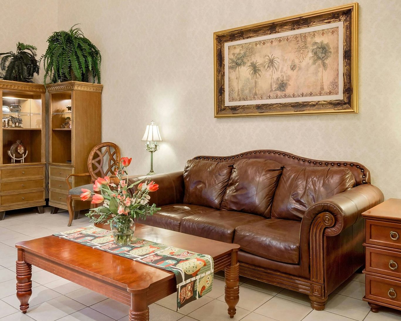 Comfortable hotel lobby with leather sofa, wooden furniture, and floral decor.