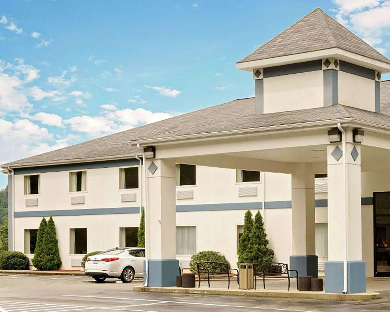 Front view of the hotel with covered entrance and parking area.