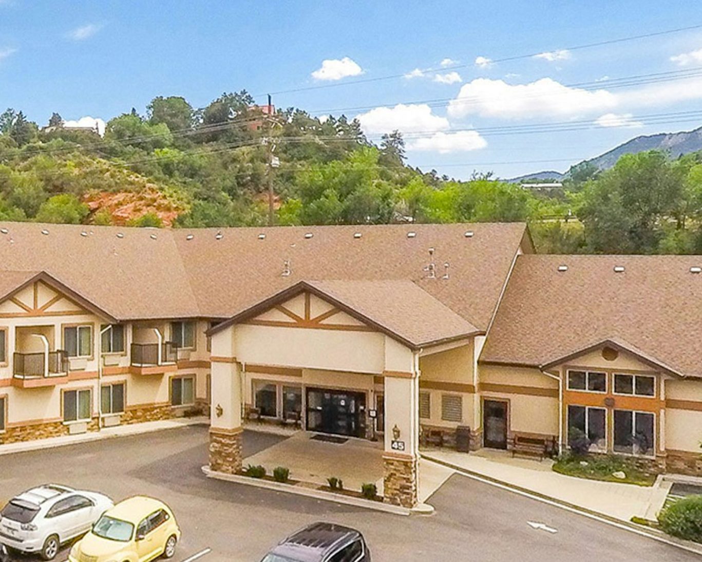 Exterior view of hotel in Manitou Springs Colorado with mountain backdrop and parking area.
