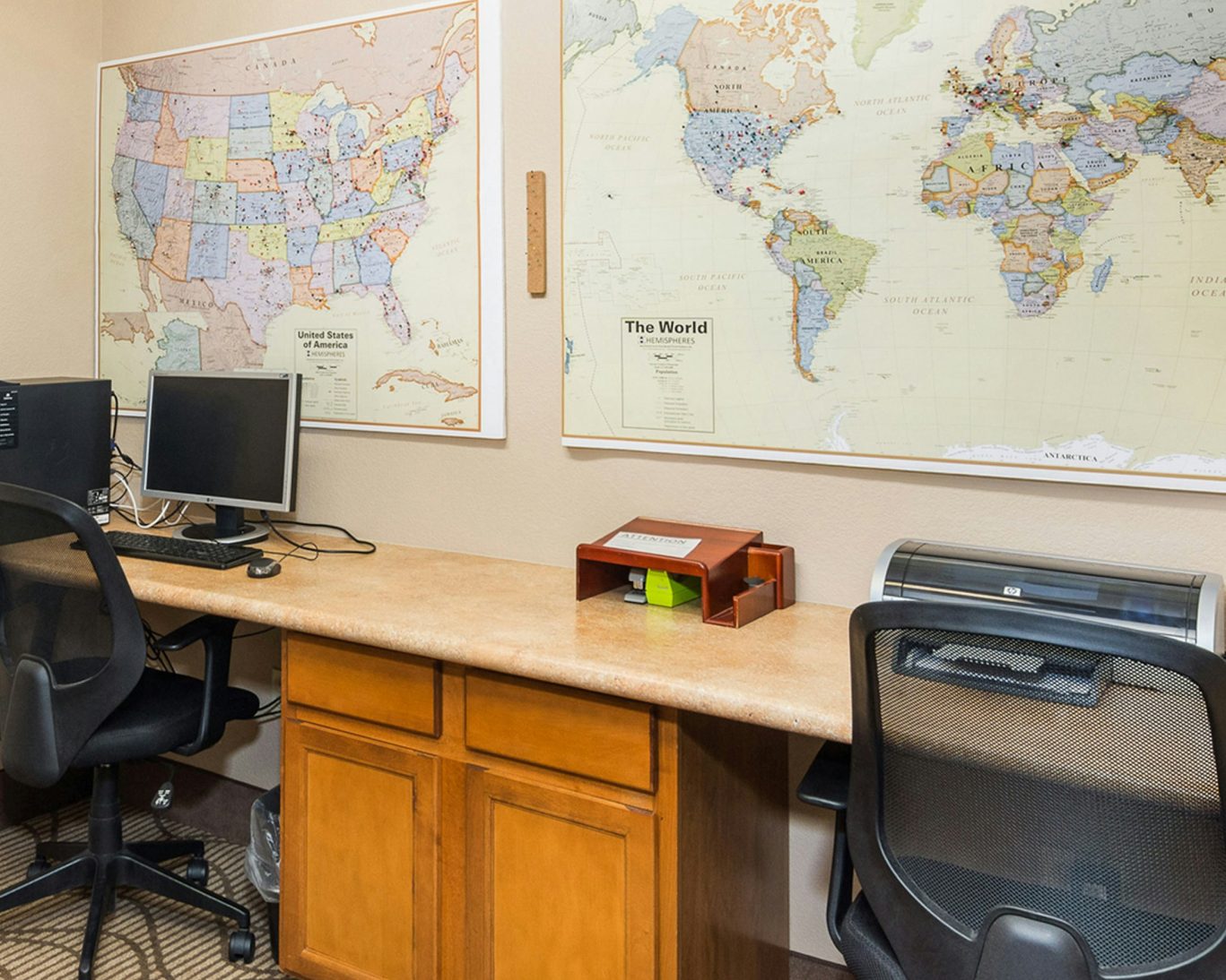Hotel business center with desktop computers, printer, and world map décor in Manitou Springs accommodation.