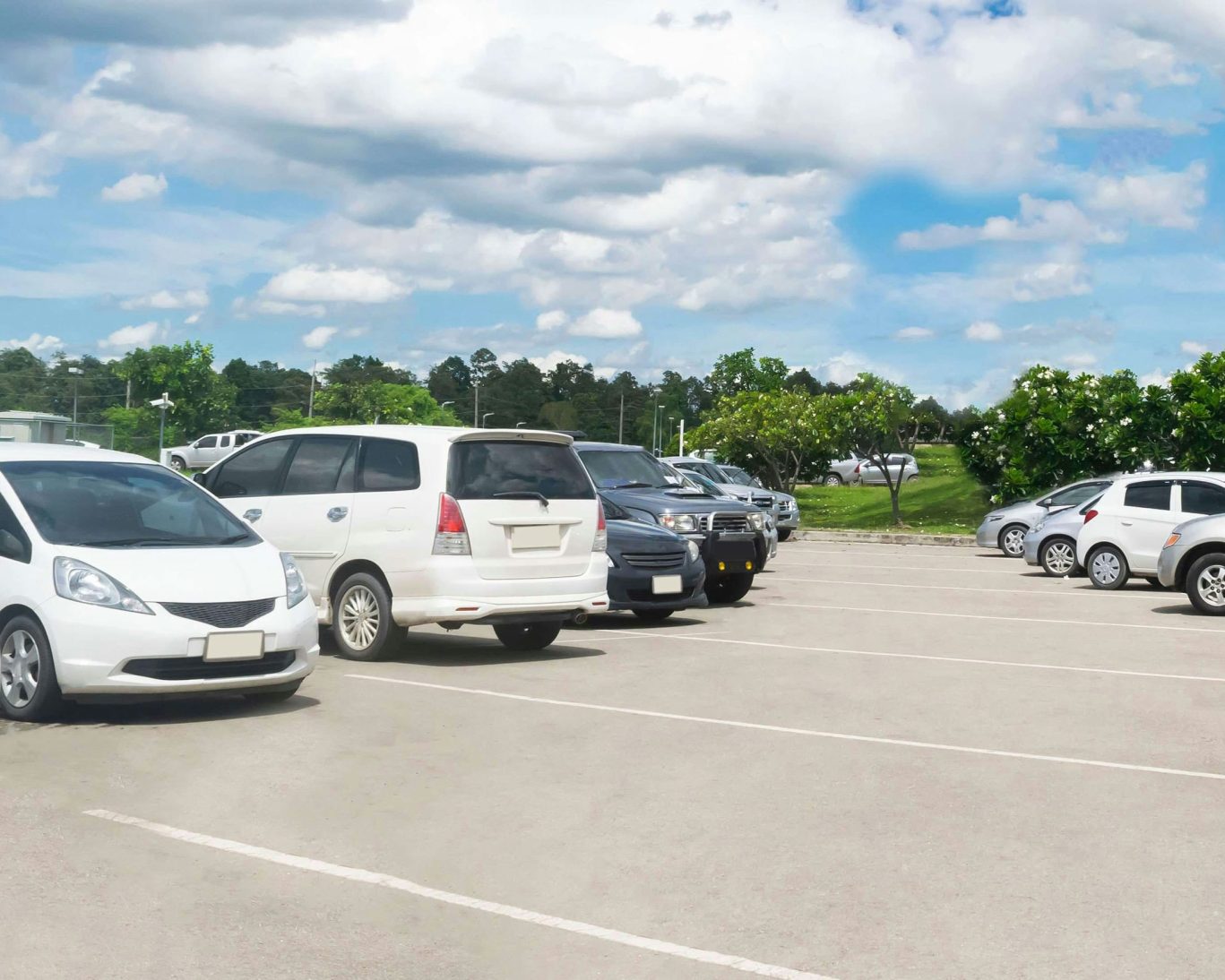 Spacious hotel parking lot with parked cars under a blue sky.