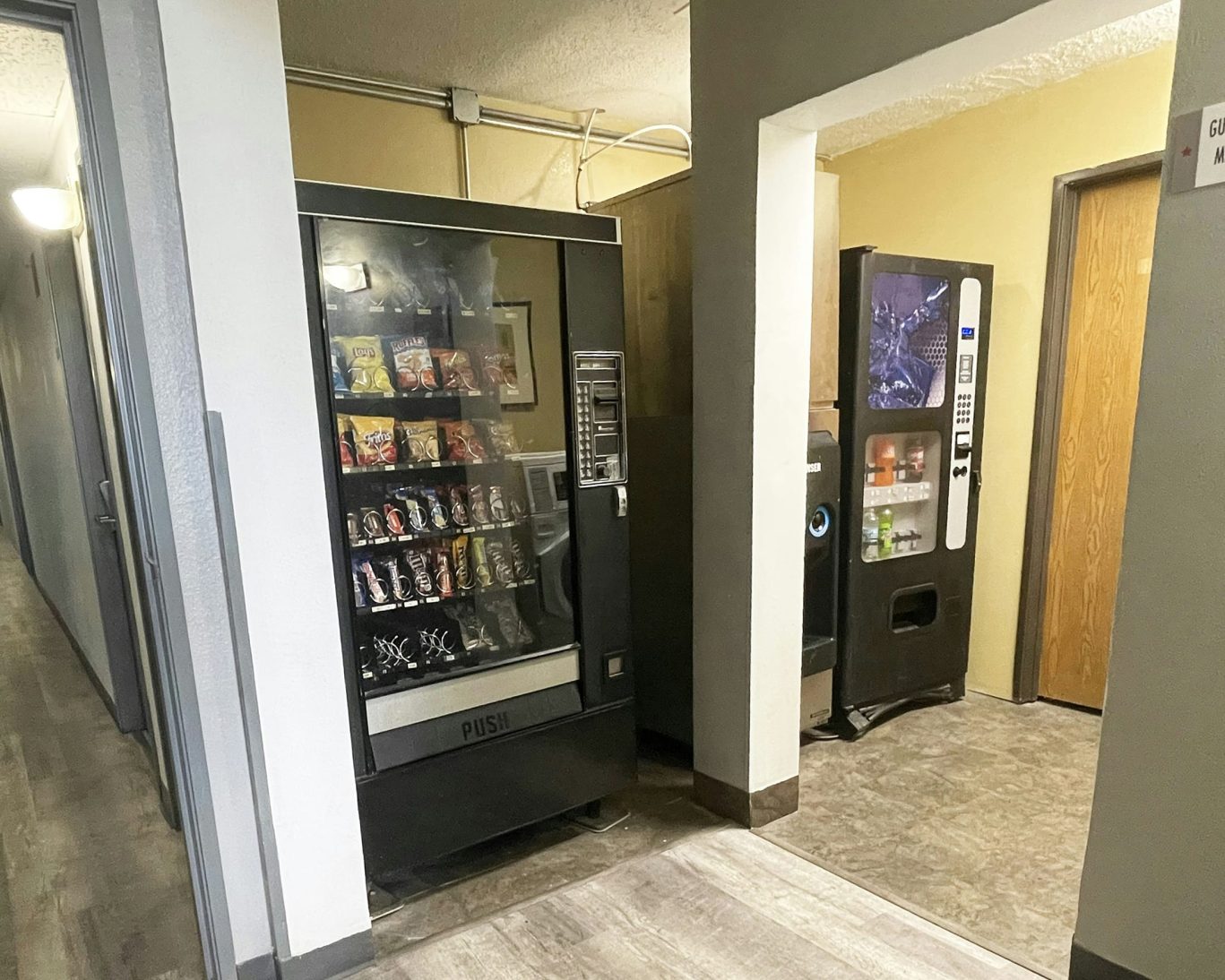 Vending machines offering snacks and beverages in hotel hallway.