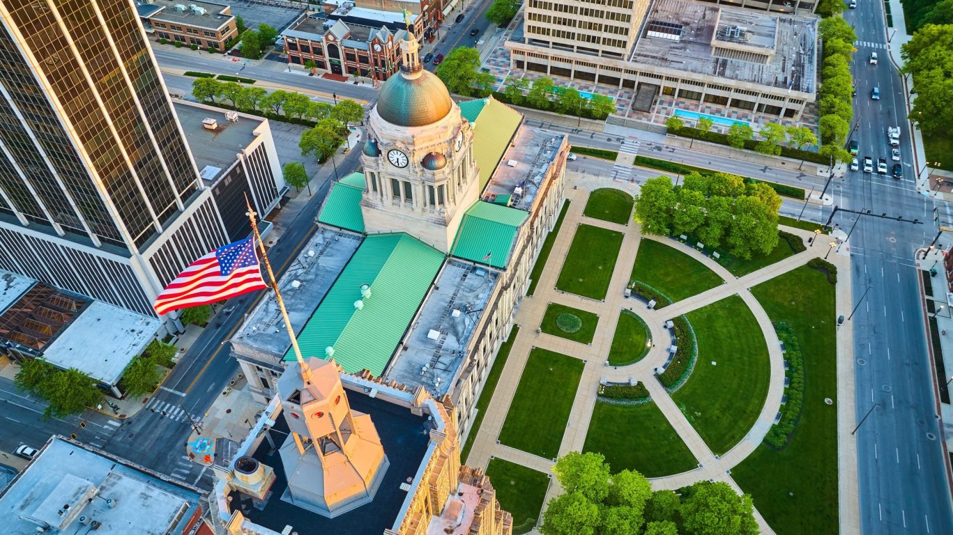 Drone shot of Fort Wayne courthouse lawn and downtown buildings with American flag.