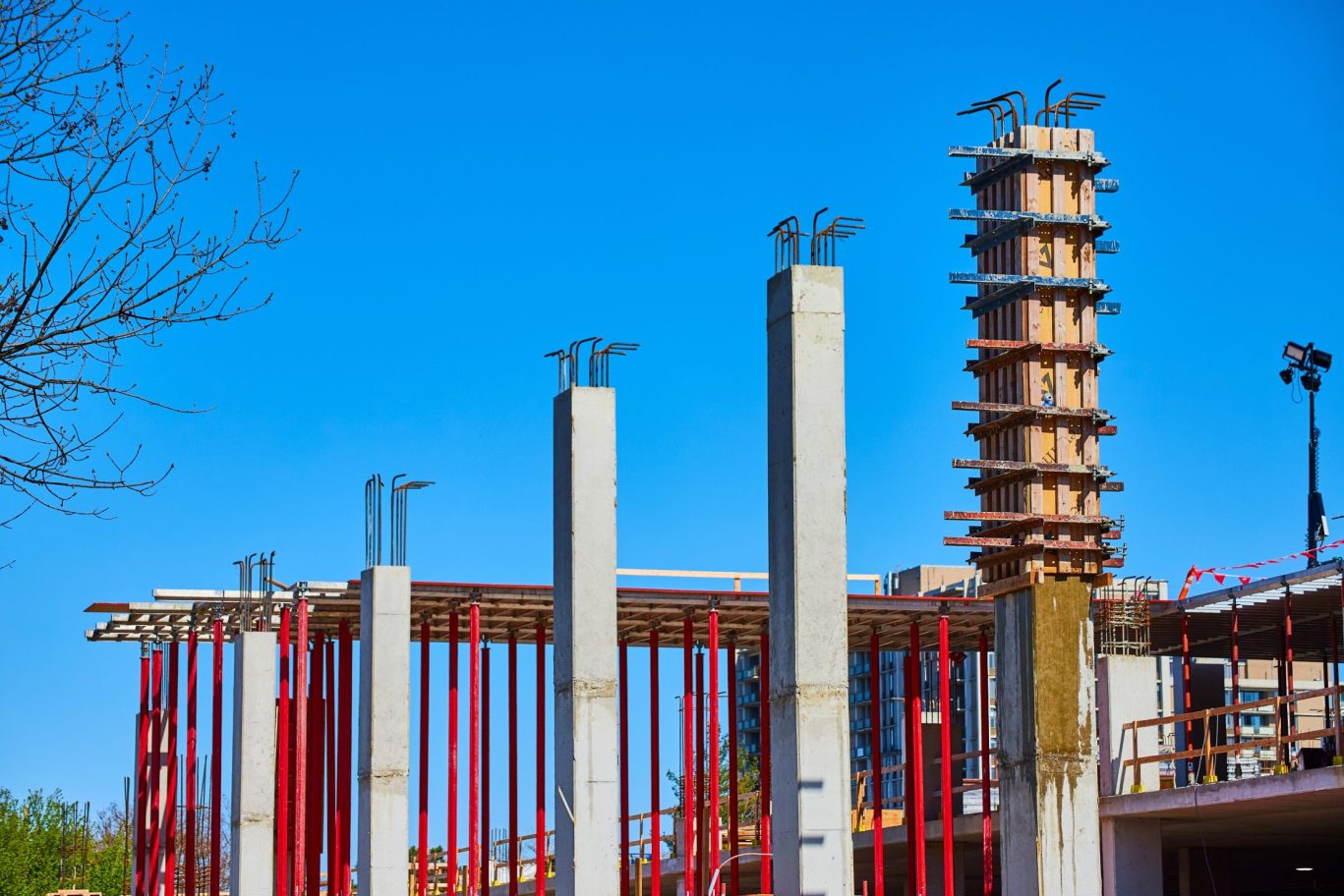 Concrete columns and support beams at a construction site under clear blue sky.