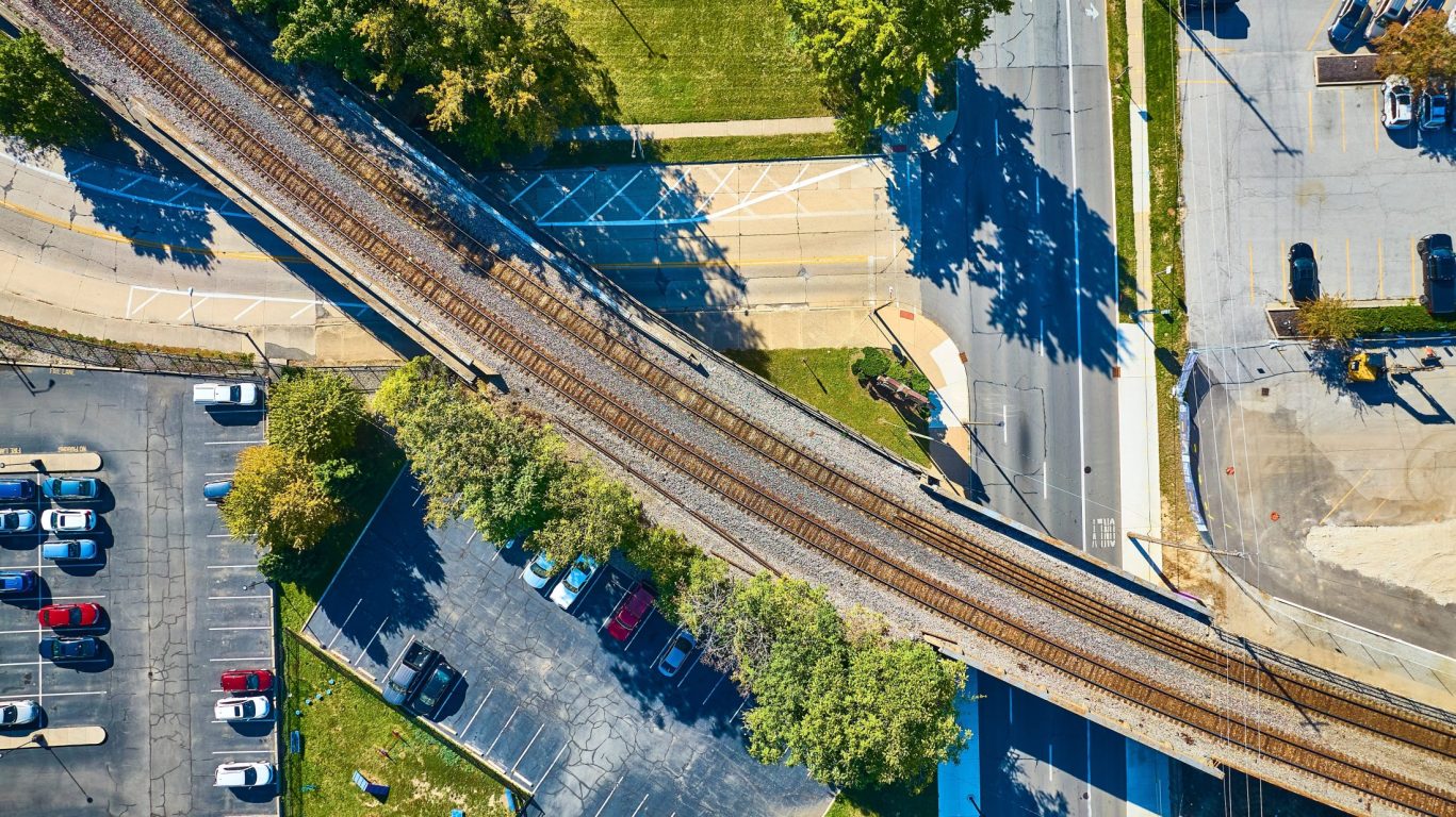 Aerial view of railroad crossing over city streets and parking lots.