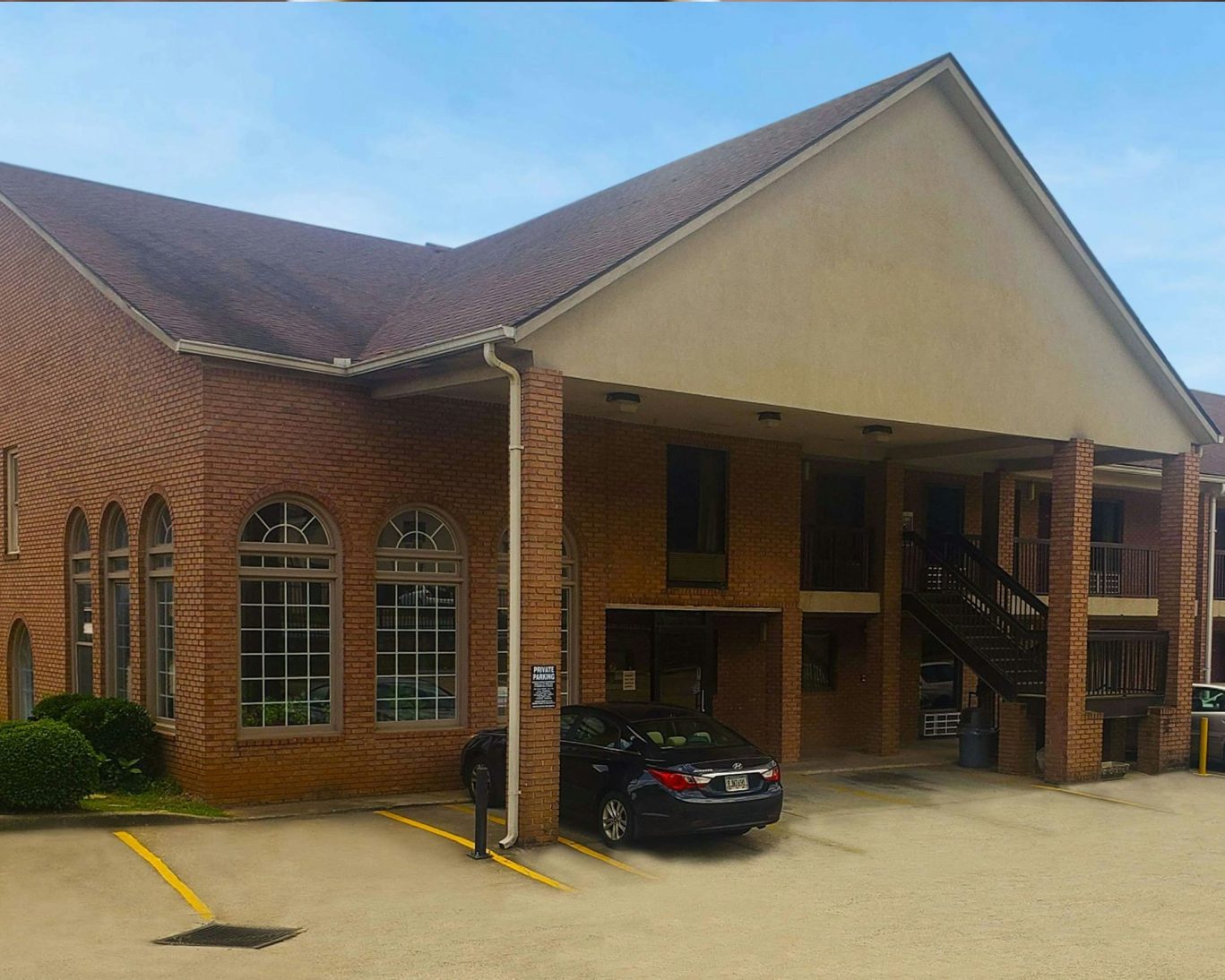 Two-story brick motel exterior with visible parking spaces and entrance.