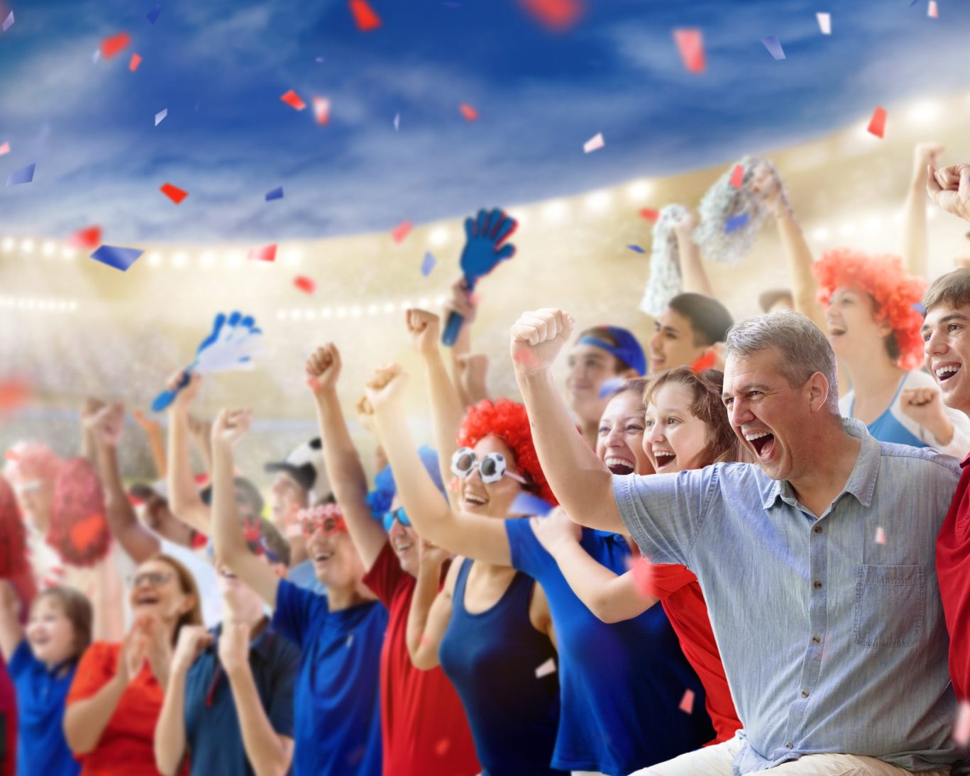 Excited sports fans cheering in stadium with confetti flying in the air.