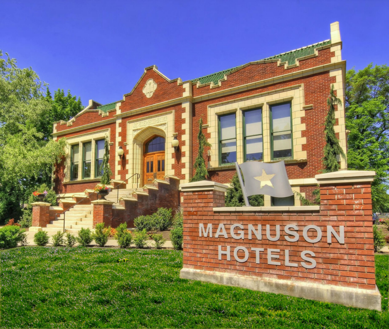 Exterior of a Magnuson Hotel building with classic brick architecture and a branded sign in front.