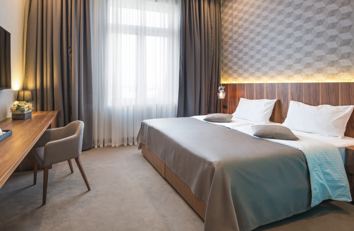 Modern hotel room with a large bed, wood accents, and a cozy work desk.