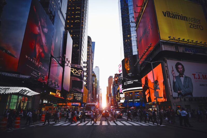 A bustling city street filled with billboards and pedestrians walking along the sidewalks.