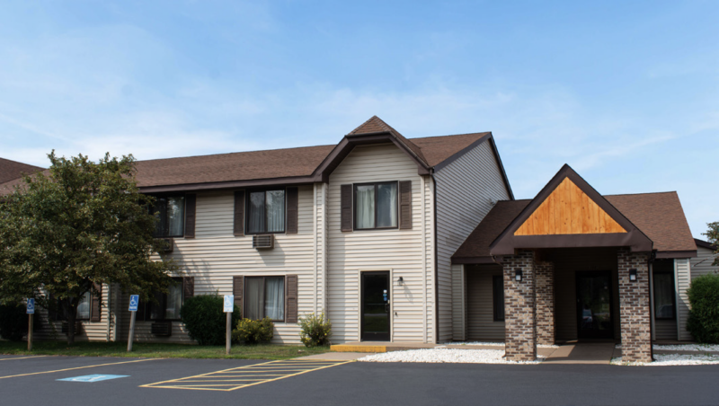 Exterior view of a Magnuson Hotel building with parking lot and accessible parking spaces.