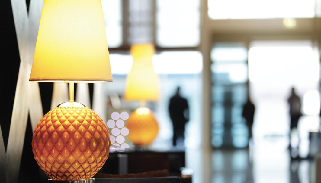Stylish hotel lobby with modern table lamp and blurred guests.
