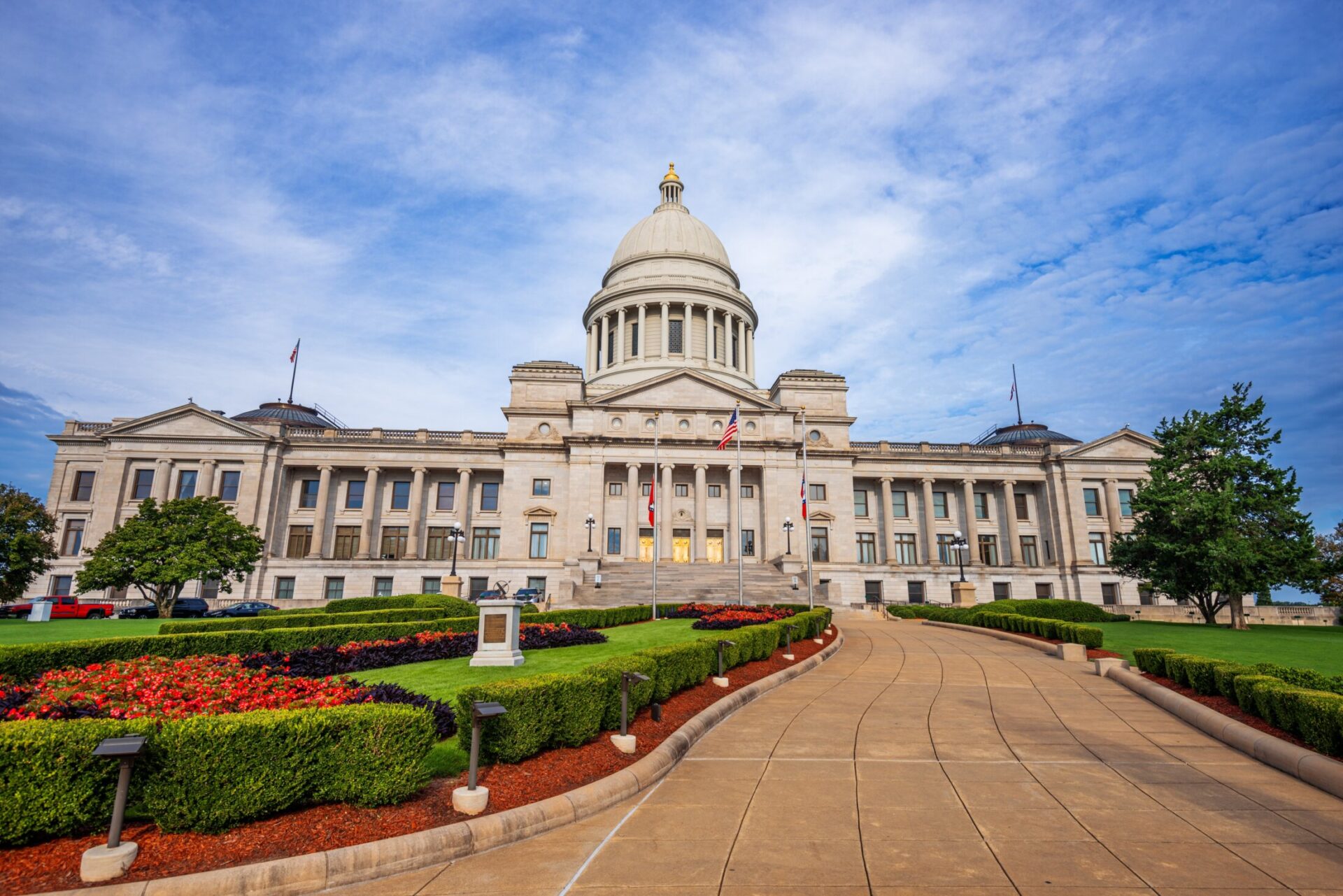 Arkansas State Capitol building in Little Rock with landscaped gardens and blue sky