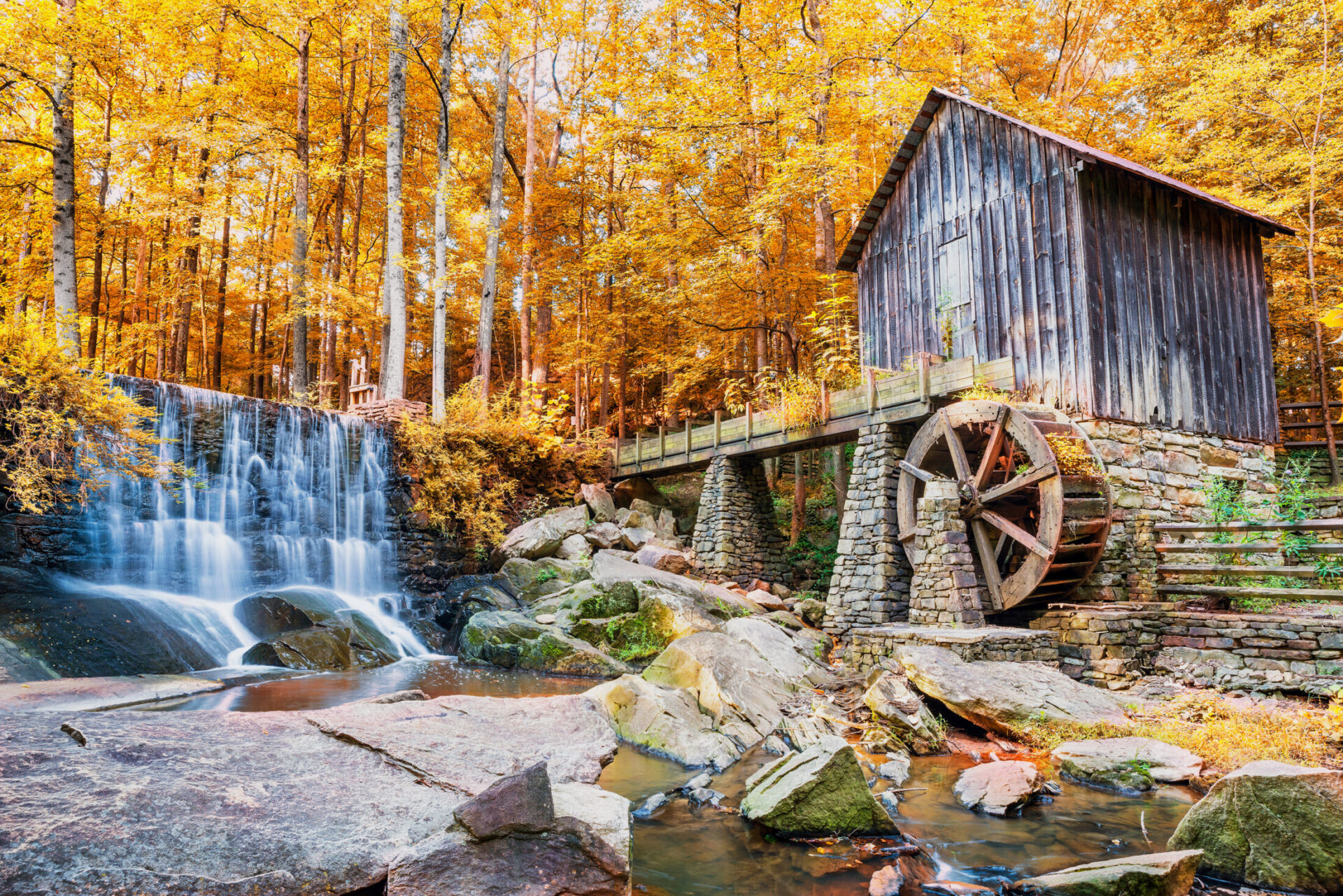 Historic wooden mill beside cascading waterfall surrounded by autumn foliage in Marietta, Georgia