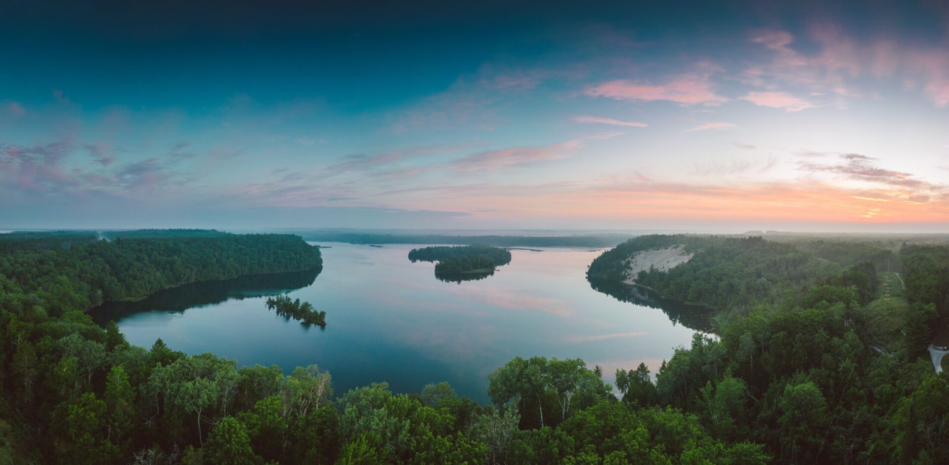Panoramic aerial view of tranquil lake and forest at sunset in Northern Michigan